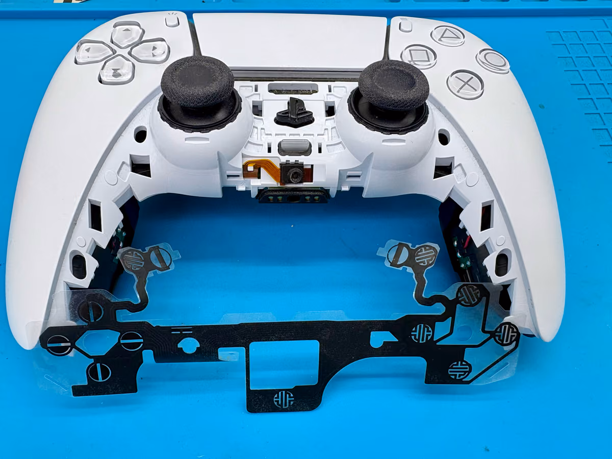 DualSense-controller geopend met de knoppen en rubberen contactmatjes zichtbaar