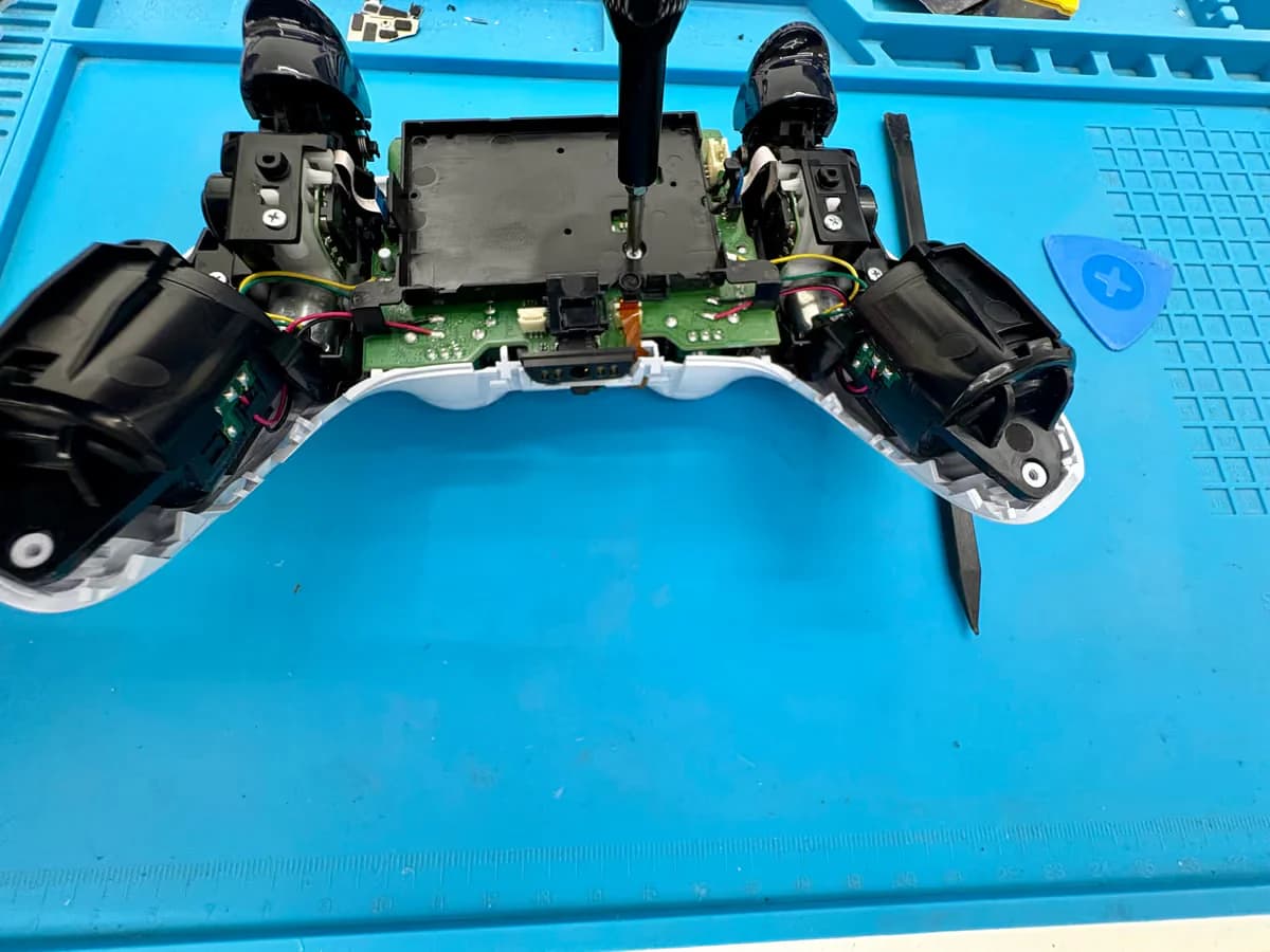 DualSense-controller geopend op de werkbank met het gereedschap zichtbaar