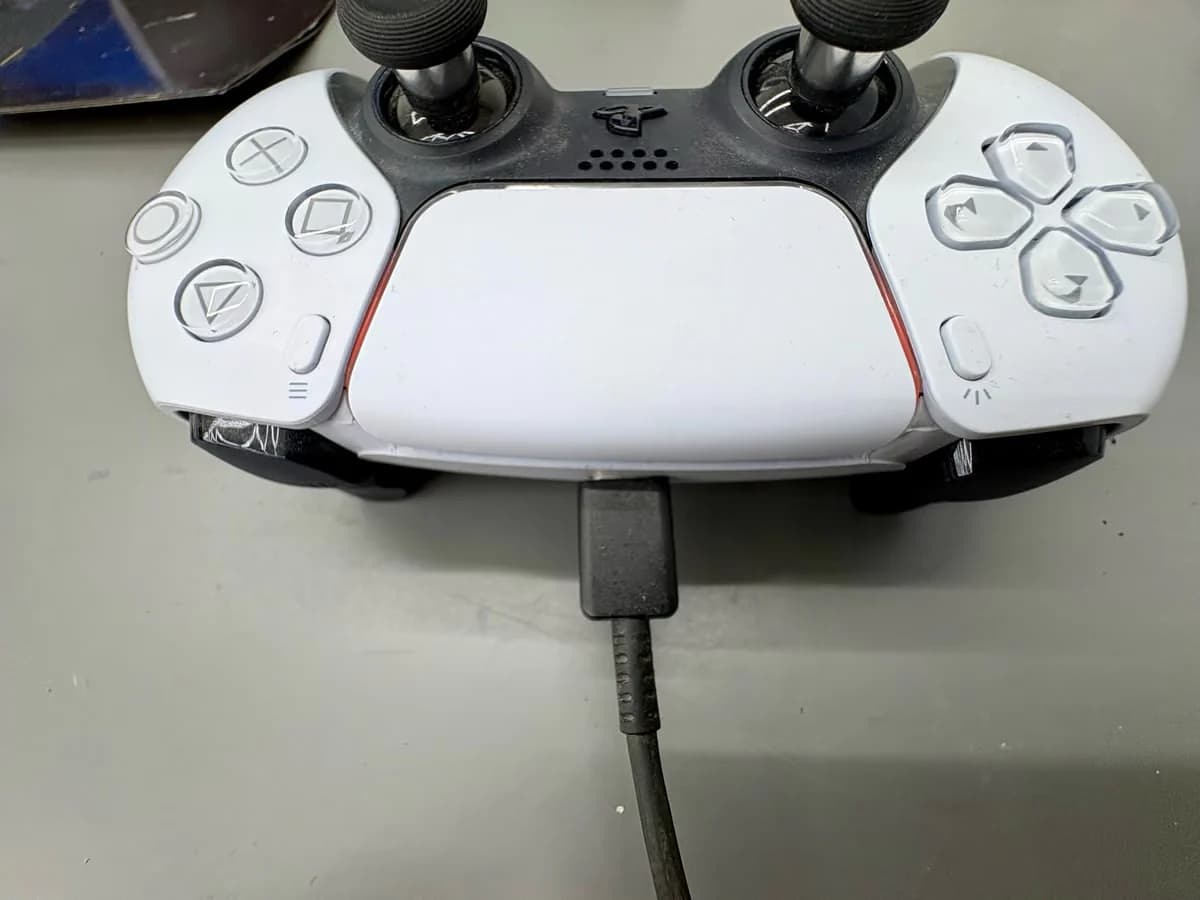 DualSense-controller met USB-C kabel aangesloten, oranje laadlampje zichtbaar