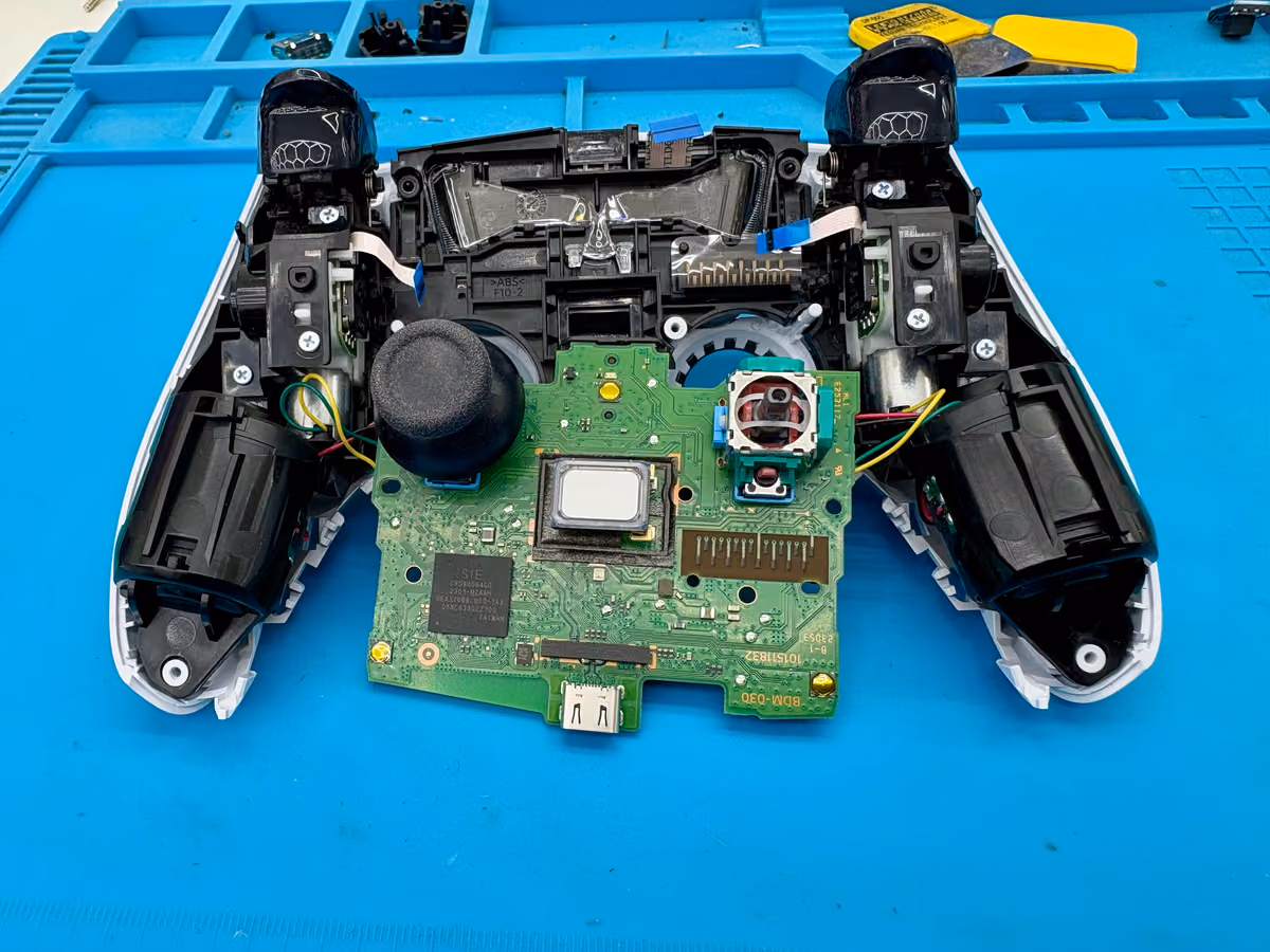 DualSense-controller geopend op de werkbank met de stickmodule zichtbaar