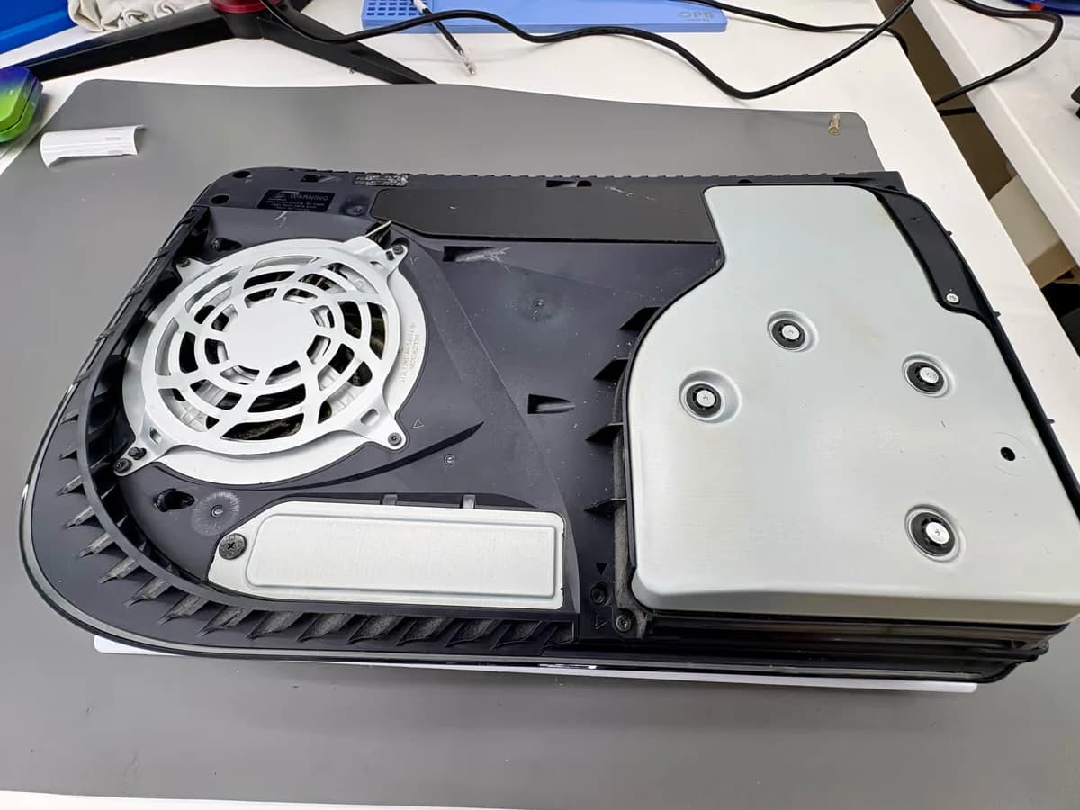 Het schijfstation van een oorspronkelijke PS5 zit met schroeven vast in de console