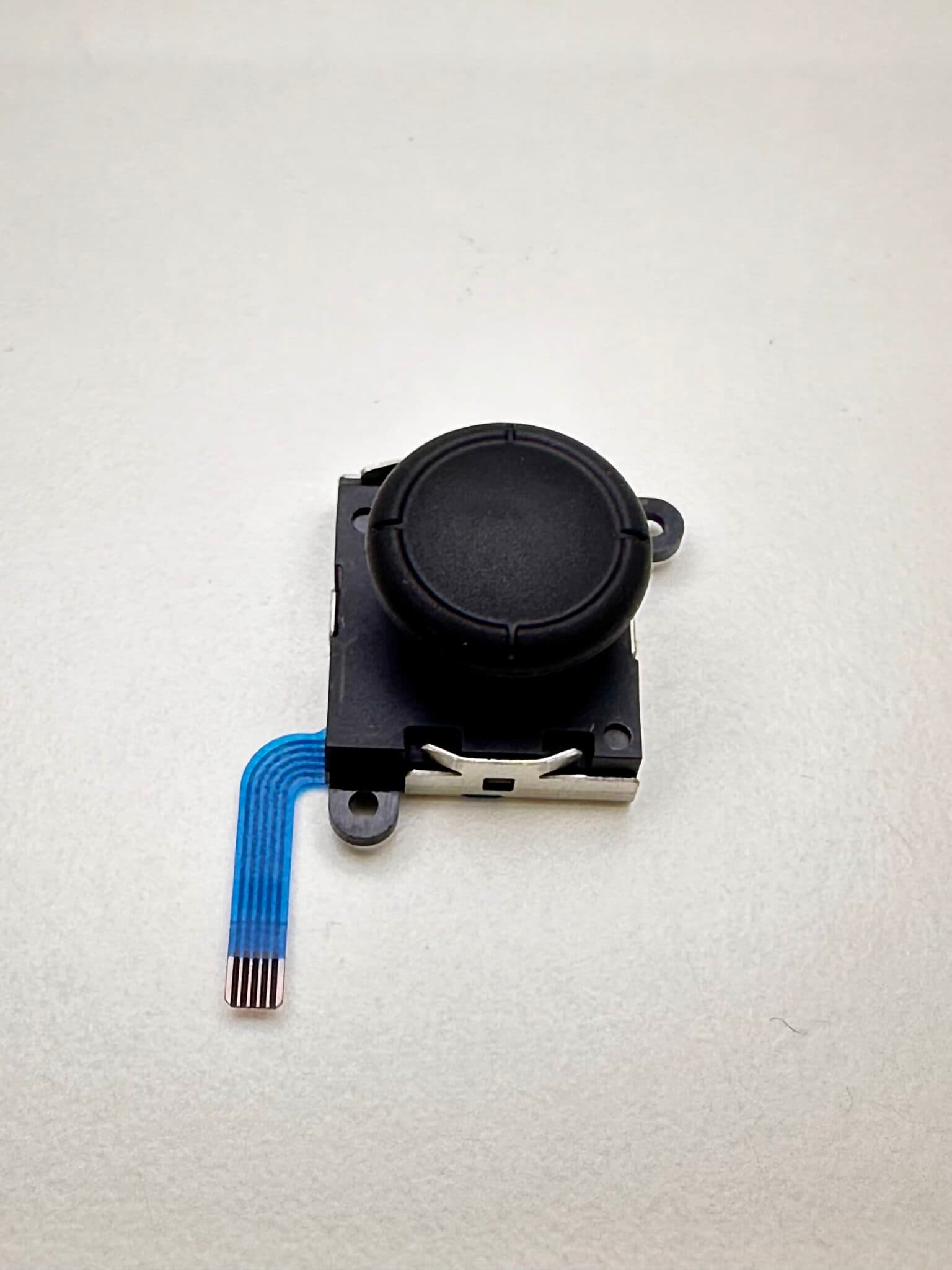 Losgenomen Joy-Con-stickmodule met blauwe flexkabel, op de werkbank bij FixMyTech in Rotterdam